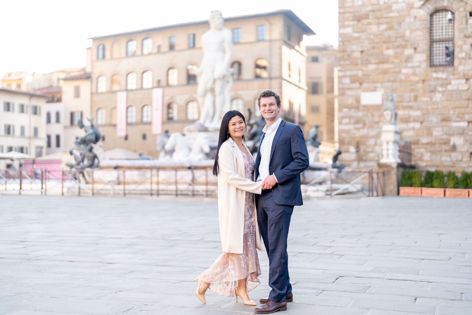 A couple shares a romantic moment in front of historic stone buildings in Florence, Italy.