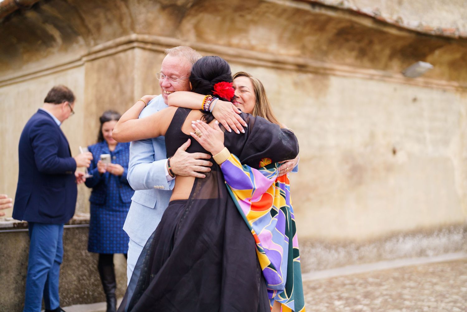 Wedding guests embracing and celebrating during an outdoor reception.
