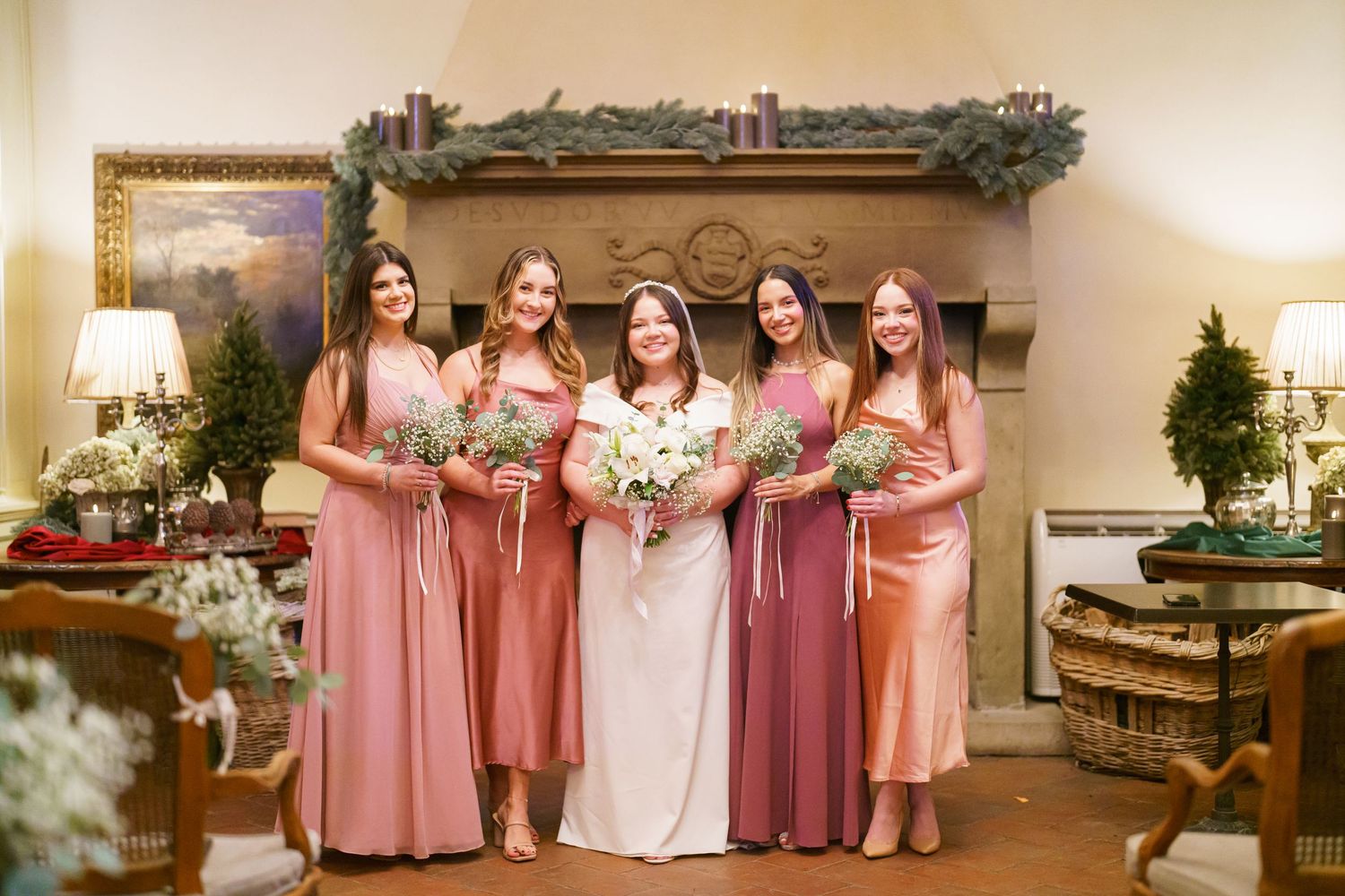 Bridesmaids in pink and burgundy dresses pose together at a wedding venue.