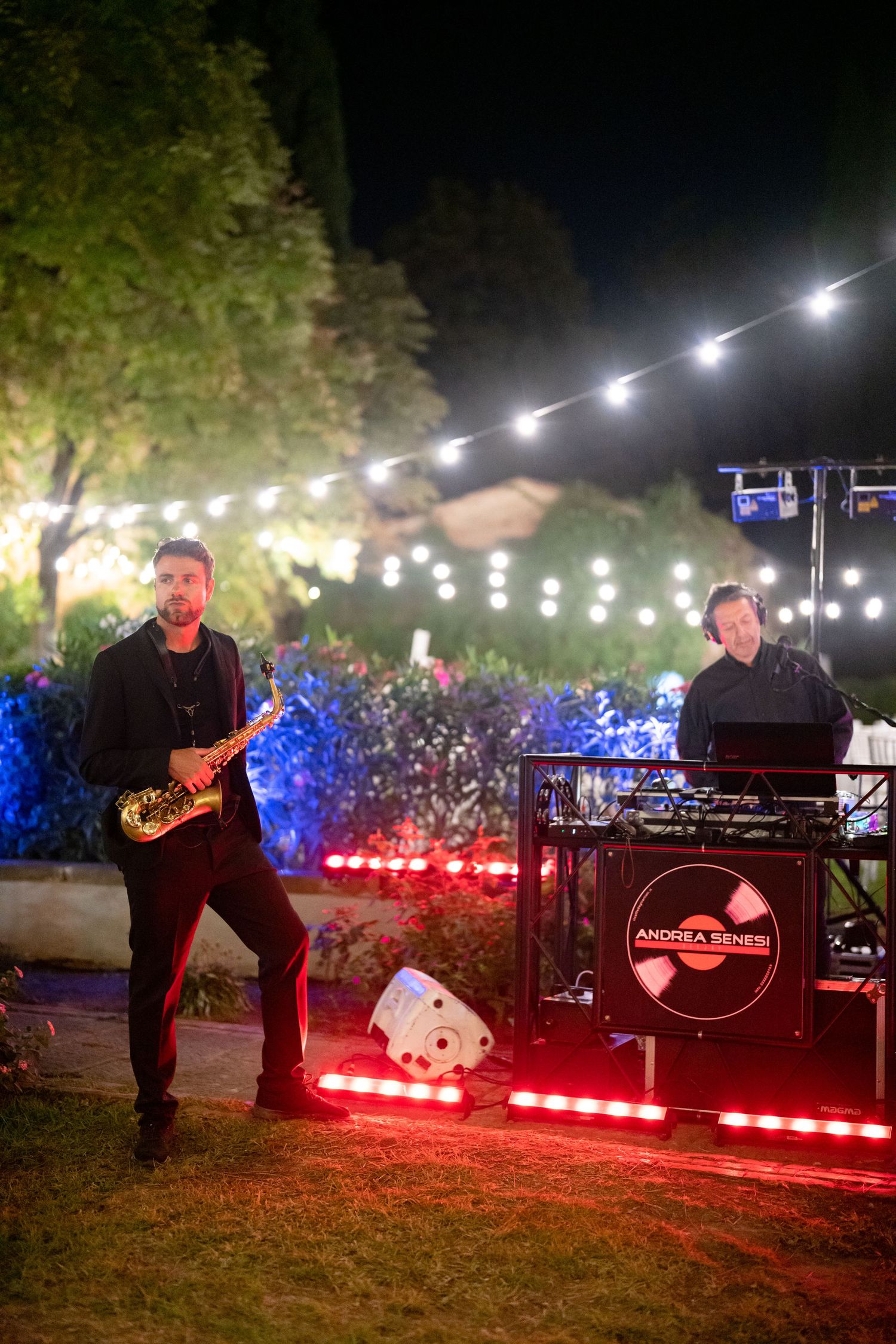 DJ setup with colorful lights and equipment for outdoor nighttime wedding entertainment.