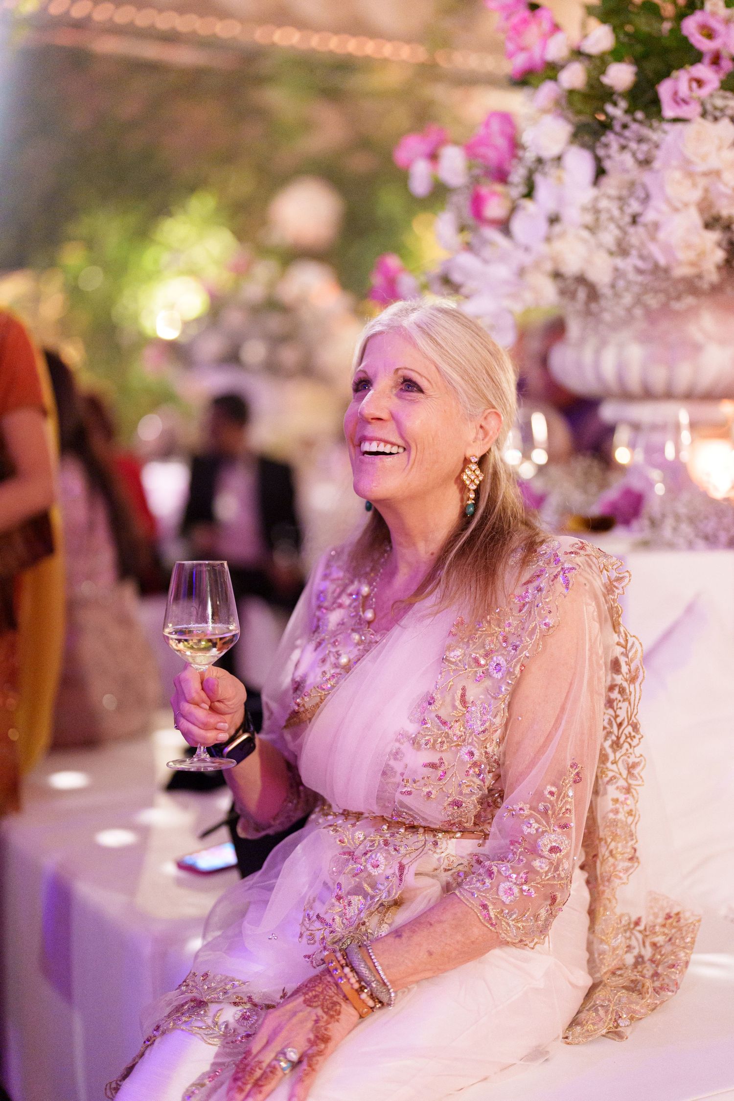 Elegant reception setting with pink floral centerpieces and soft purple mood lighting.