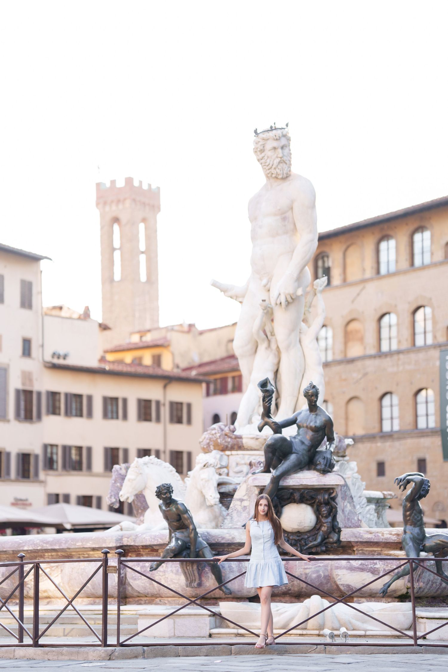 A scenic view of the Neptune Fountain in Piazza della Signoria, Florence, with historic buildings and tower in background.