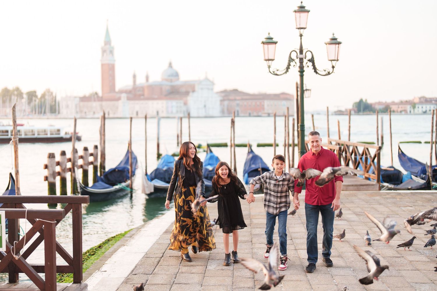 Panoramic view of Venice's St Mark's Square with lamp posts and people walking along the waterfront promenade.