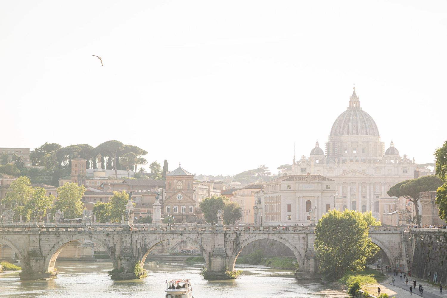 Scenic view of Rome with St. Peter's Basilica dome, Tiber River, and Ponte Sant'Angelo bridge in golden morning light.