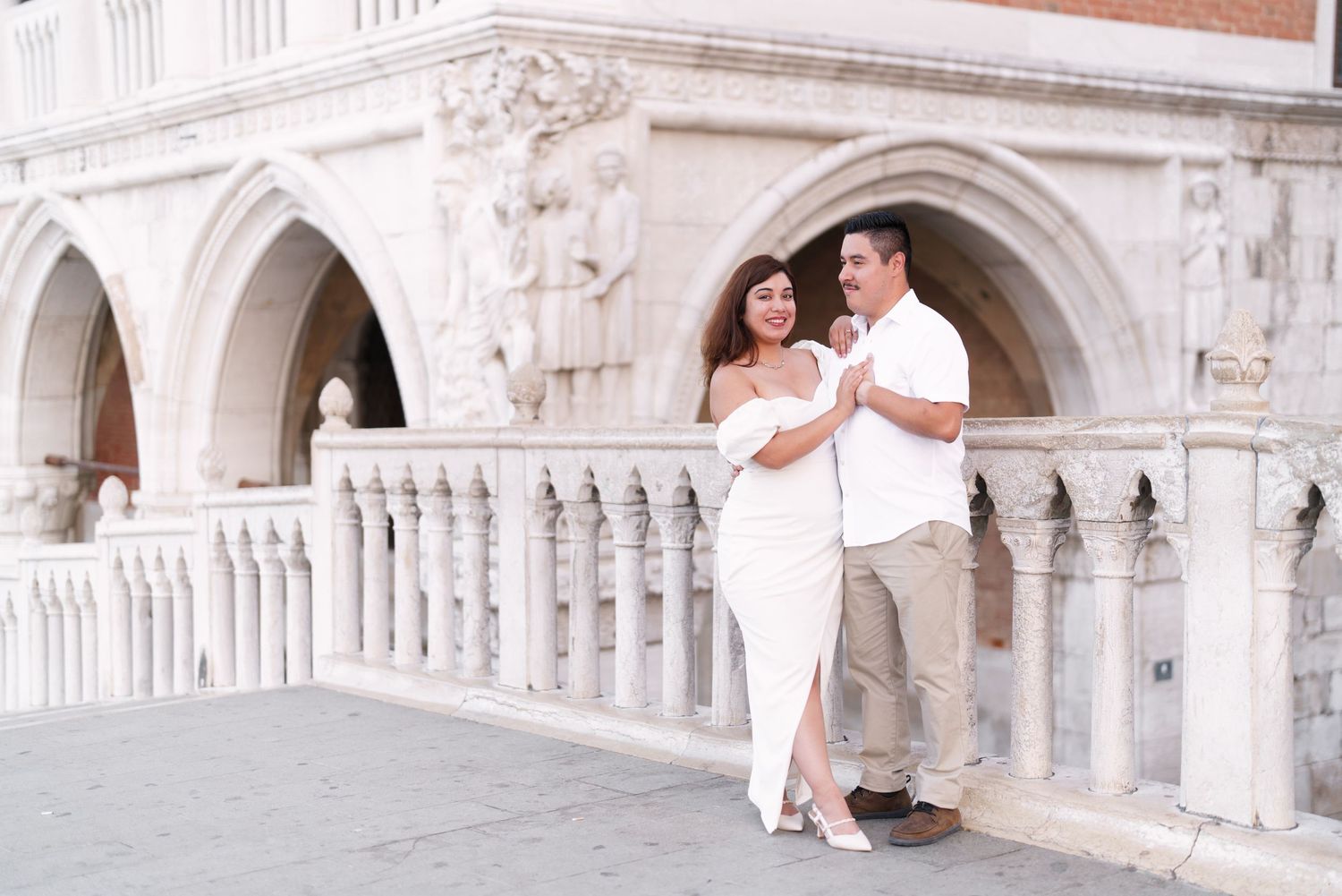 Couple in white outfits poses for romantic photos at Venice's ornate Doge's Palace and Bridge of Sighs.