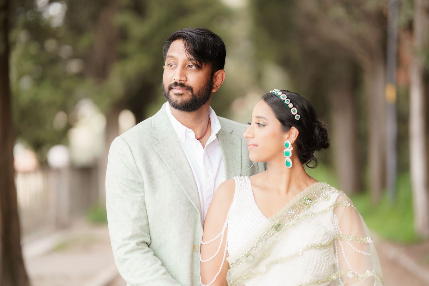 A couple in traditional Indian wedding attire share romantic moments during an outdoor photo session.