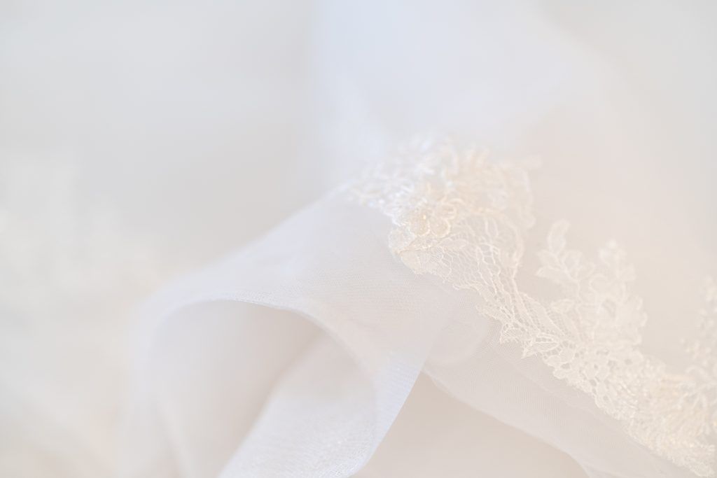 White satin ribbon and lace details laid out on a soft neutral background.