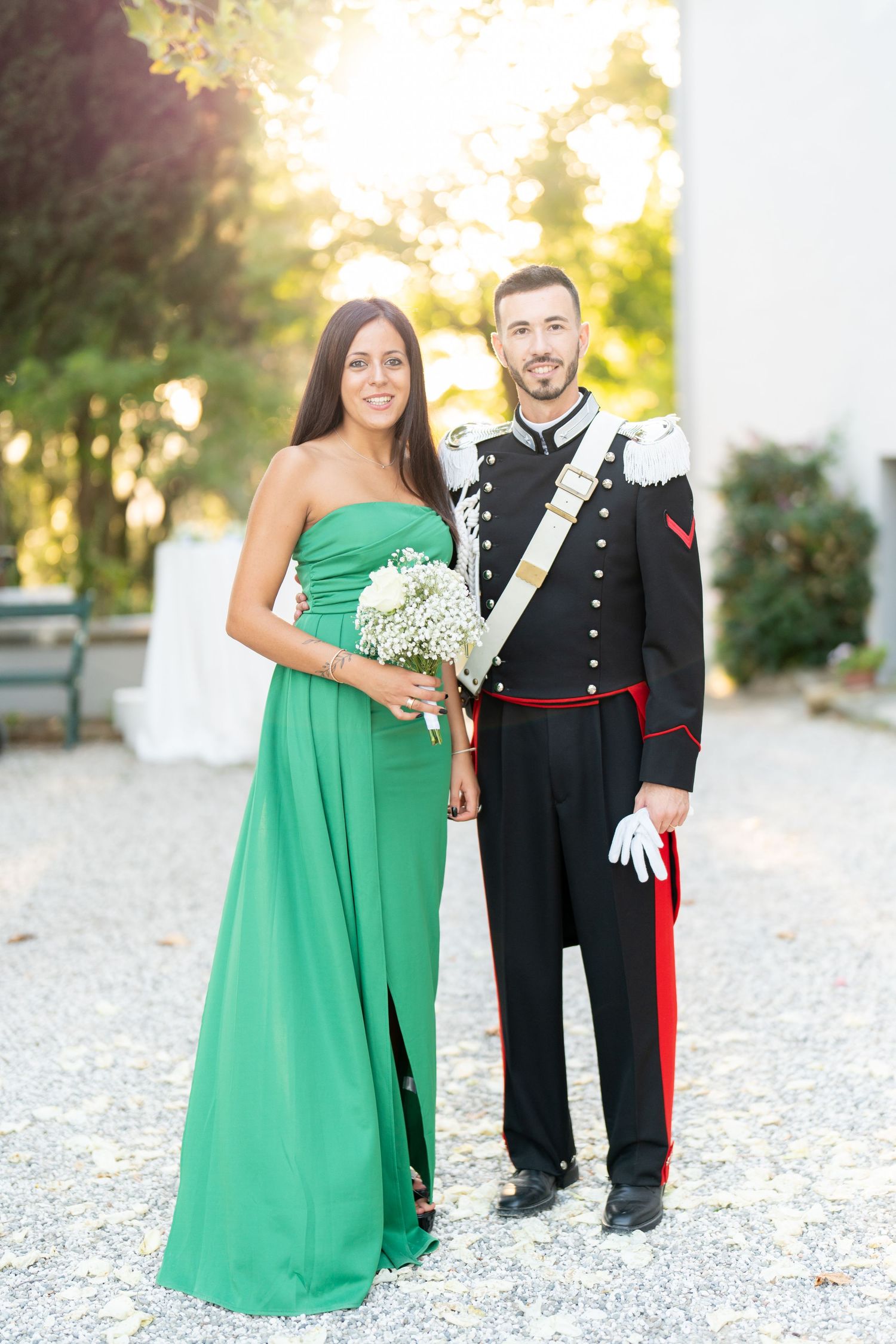 Formal couple in green gown and military dress uniform at outdoor event.