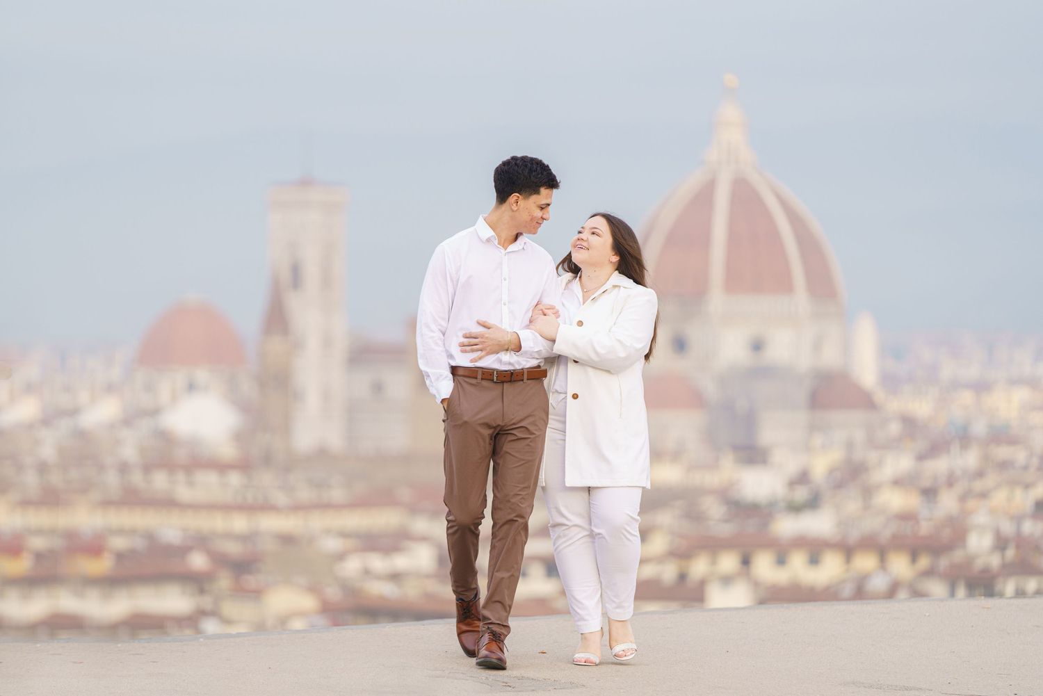 Couple shares romantic moment overlooking Florence skyline with iconic Duomo cathedral in background.