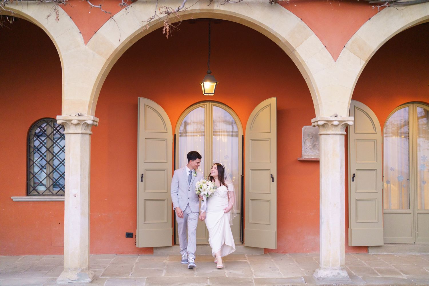 Elegant arched walkway with coral-colored walls and stone columns creating a Mediterranean architectural ambiance.