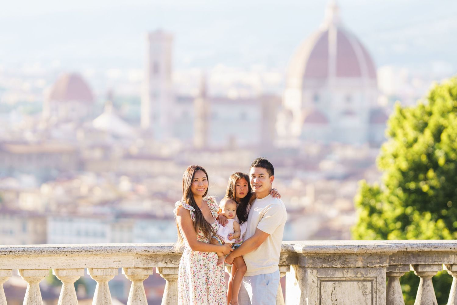 Family of three posing on a terrace with Florence cathedral dome and cityscape in the background.