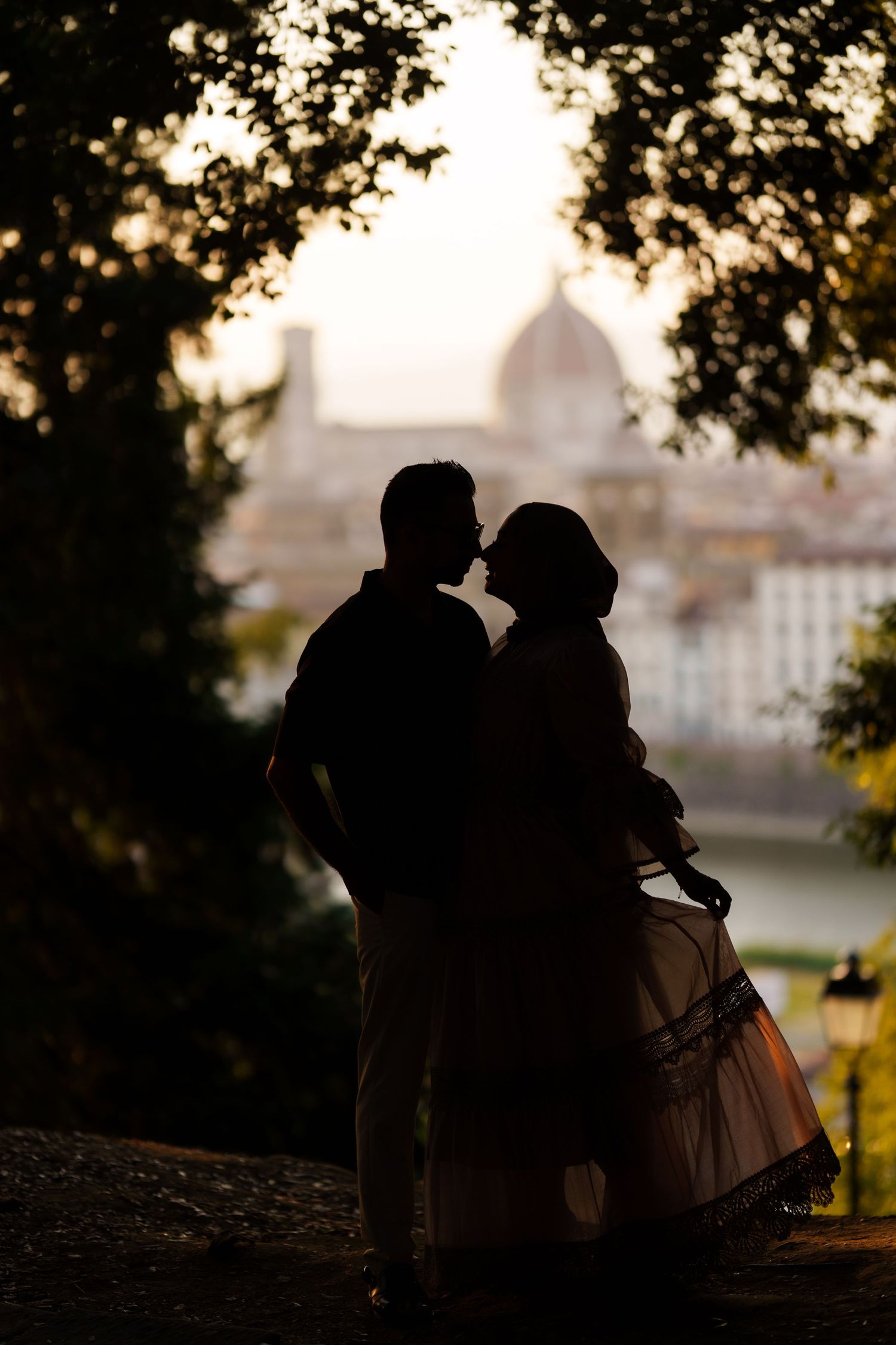 Silhouette of a couple kissing at sunset with Florence cathedral dome in the background.