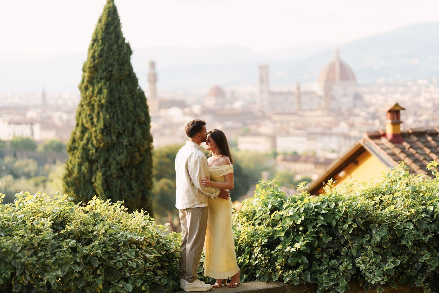 Romantic couple embracing on a terrace overlooking Florence skyline with the Duomo and cypress trees.