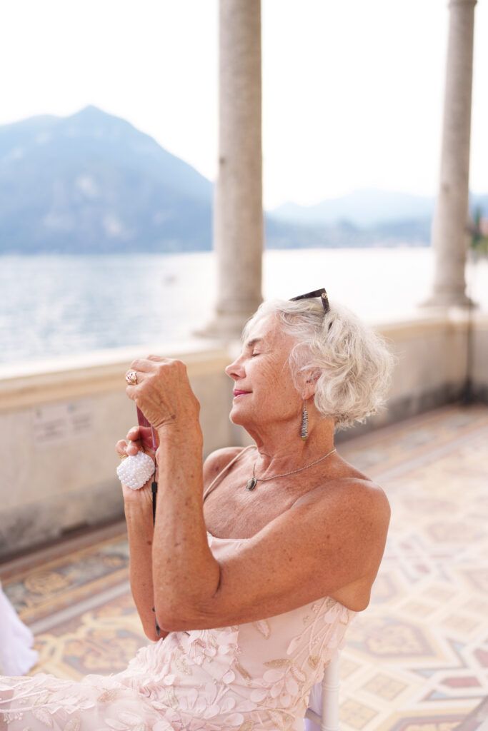 Person in formal wear laughing joyfully on a scenic balcony with mountain views.