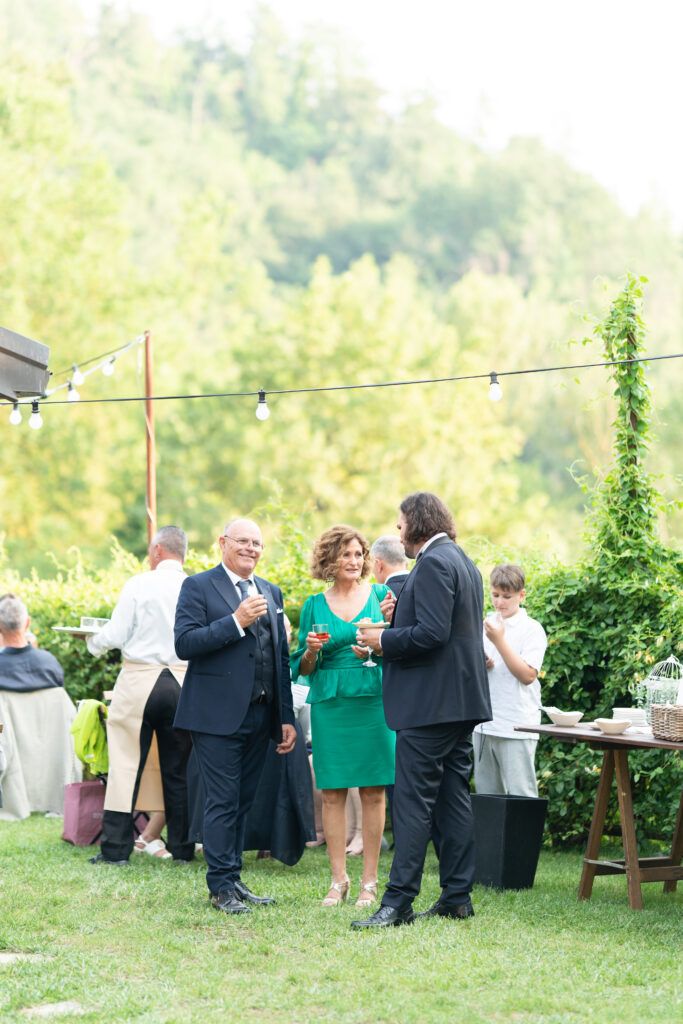 Guests socialize on a grassy lawn during an outdoor wedding reception with string lights.
