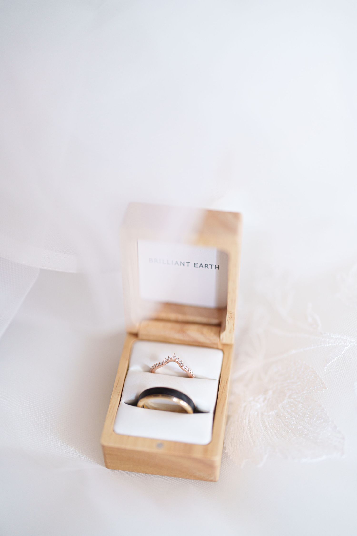 Wedding rings nestled in a wooden box with elegant packaging.