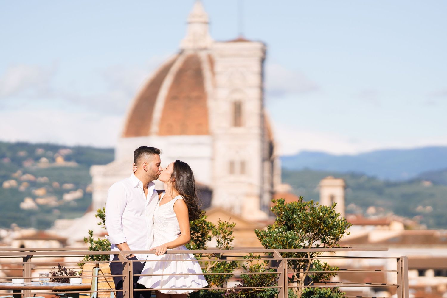Romantic couple enjoying sunset views of Florence's iconic Duomo cathedral from a rooftop terrace.