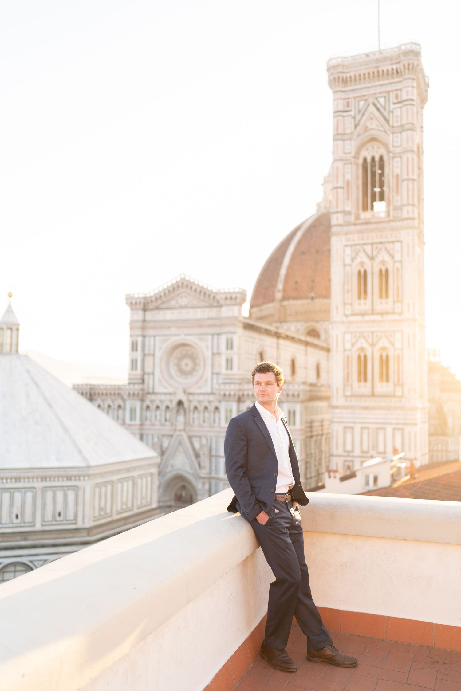 A person sits on a rooftop terrace overlooking the historic Florence Cathedral and Duomo during golden hour in Italy.