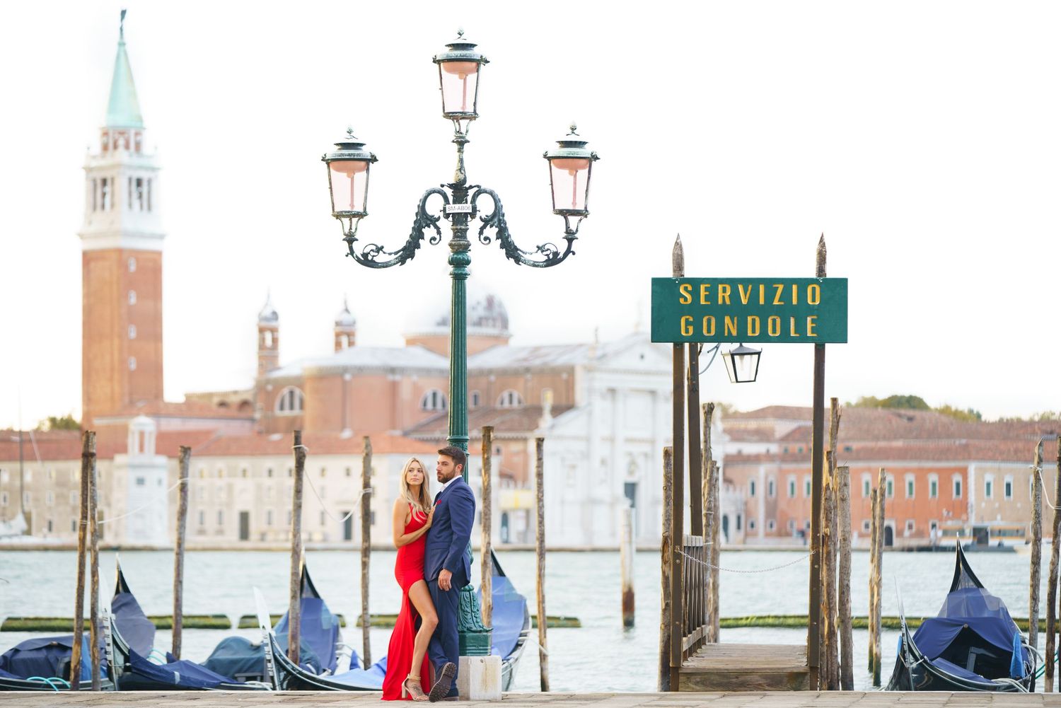 Scenic view of Venice's San Giorgio Maggiore island with ornate street lamps and waterfront promenade in the foreground.