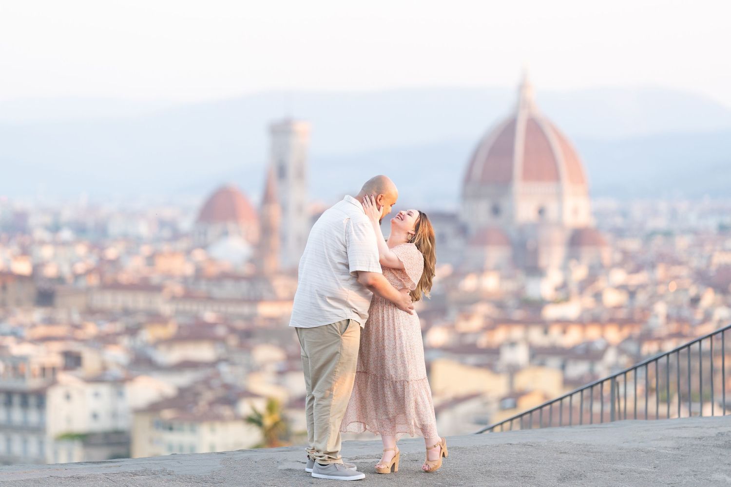 A couple shares a romantic moment overlooking the stunning cityscape of Florence, Italy from Piazzale Michelangelo.