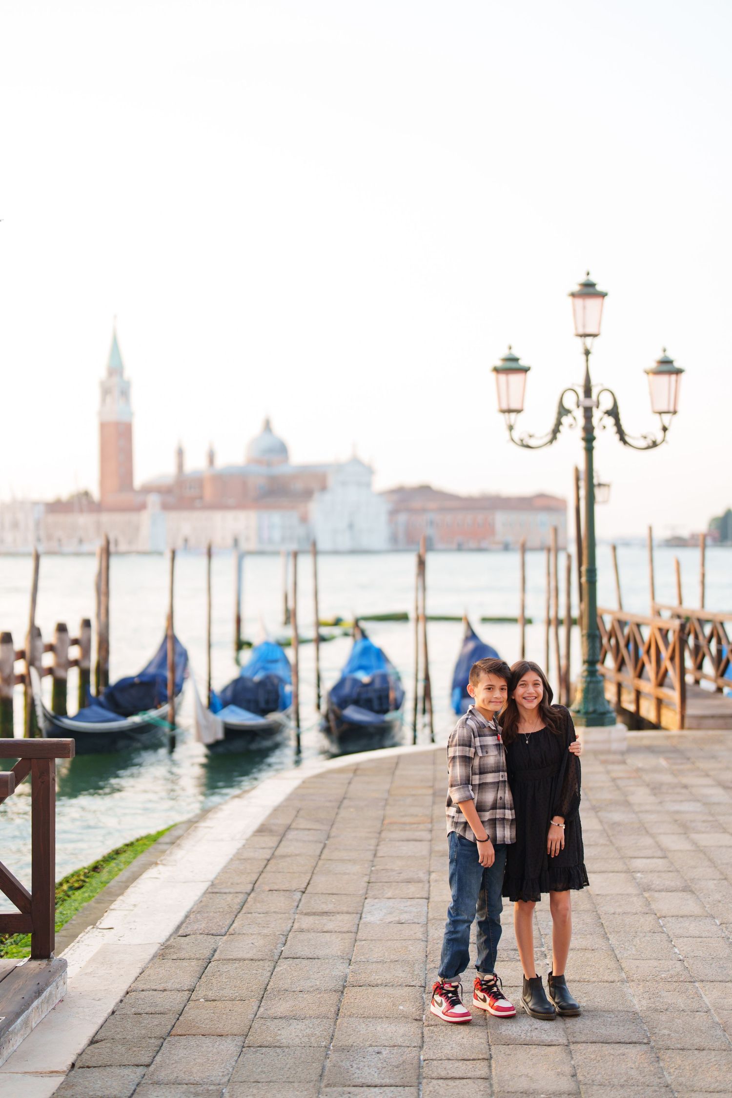 Romantic couple portraits on Venice waterfront with gondolas and historic architecture in the background.