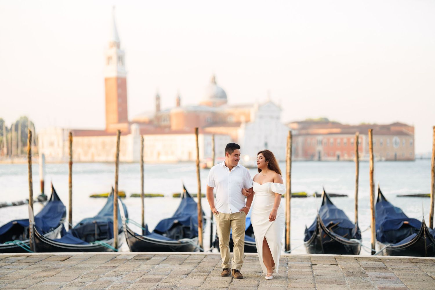 Romantic couple performs elegant dance poses along Venice's Grand Canal with gondolas and San Giorgio Maggiore in background.