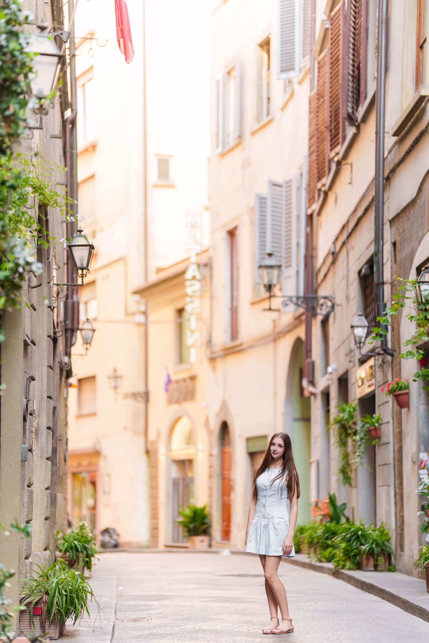 Charming narrow street in an Italian town with traditional architecture and potted plants along the walls.