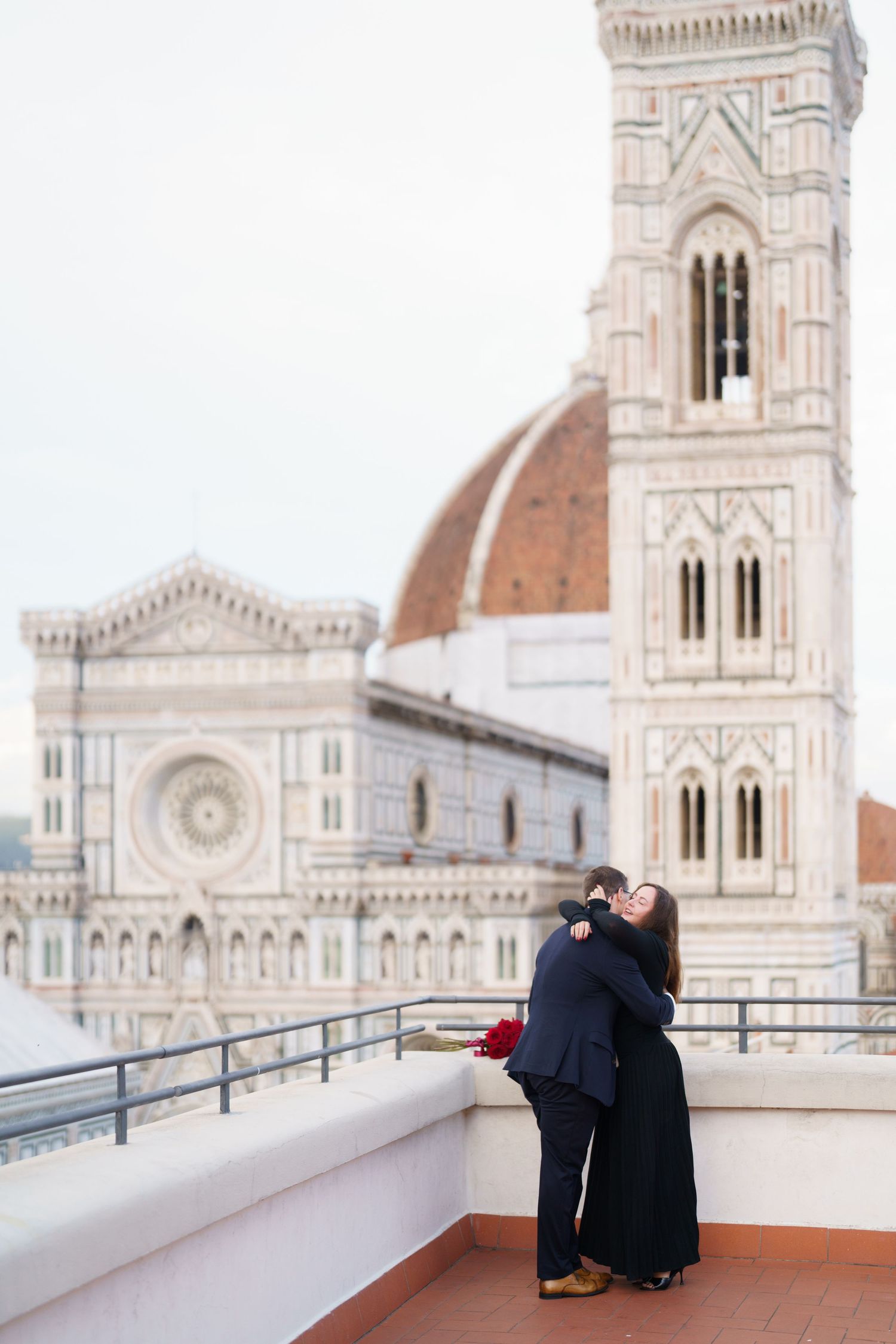 Two people share a romantic moment on a rooftop terrace overlooking the historic Florence Cathedral in Italy.