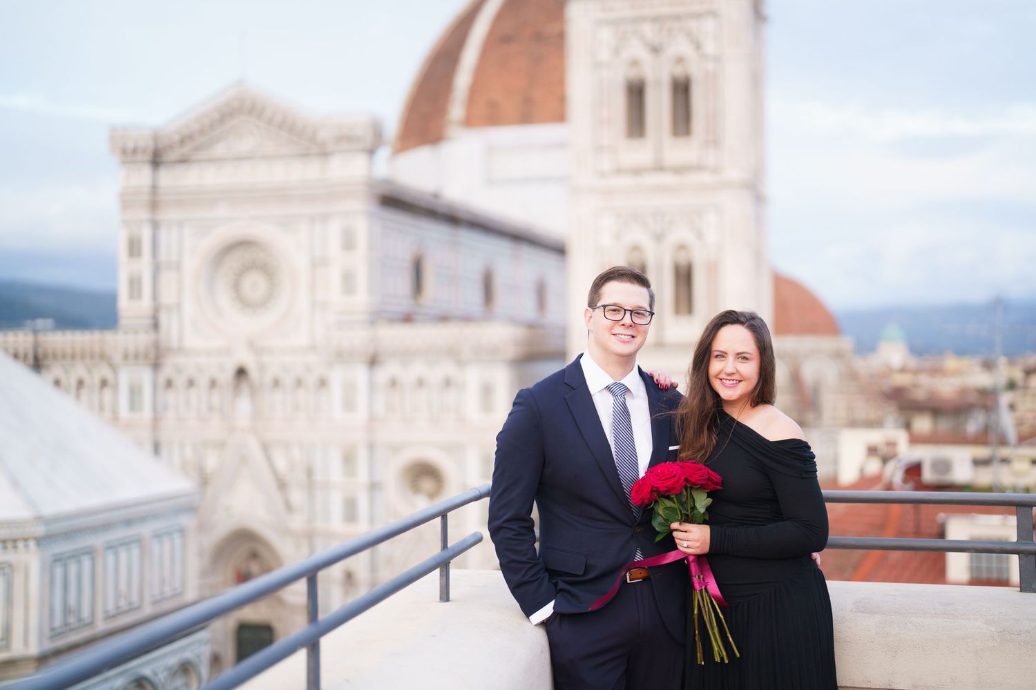A couple poses for romantic photos at various spots around Florence Cathedral in Italy during a destination engagement session.