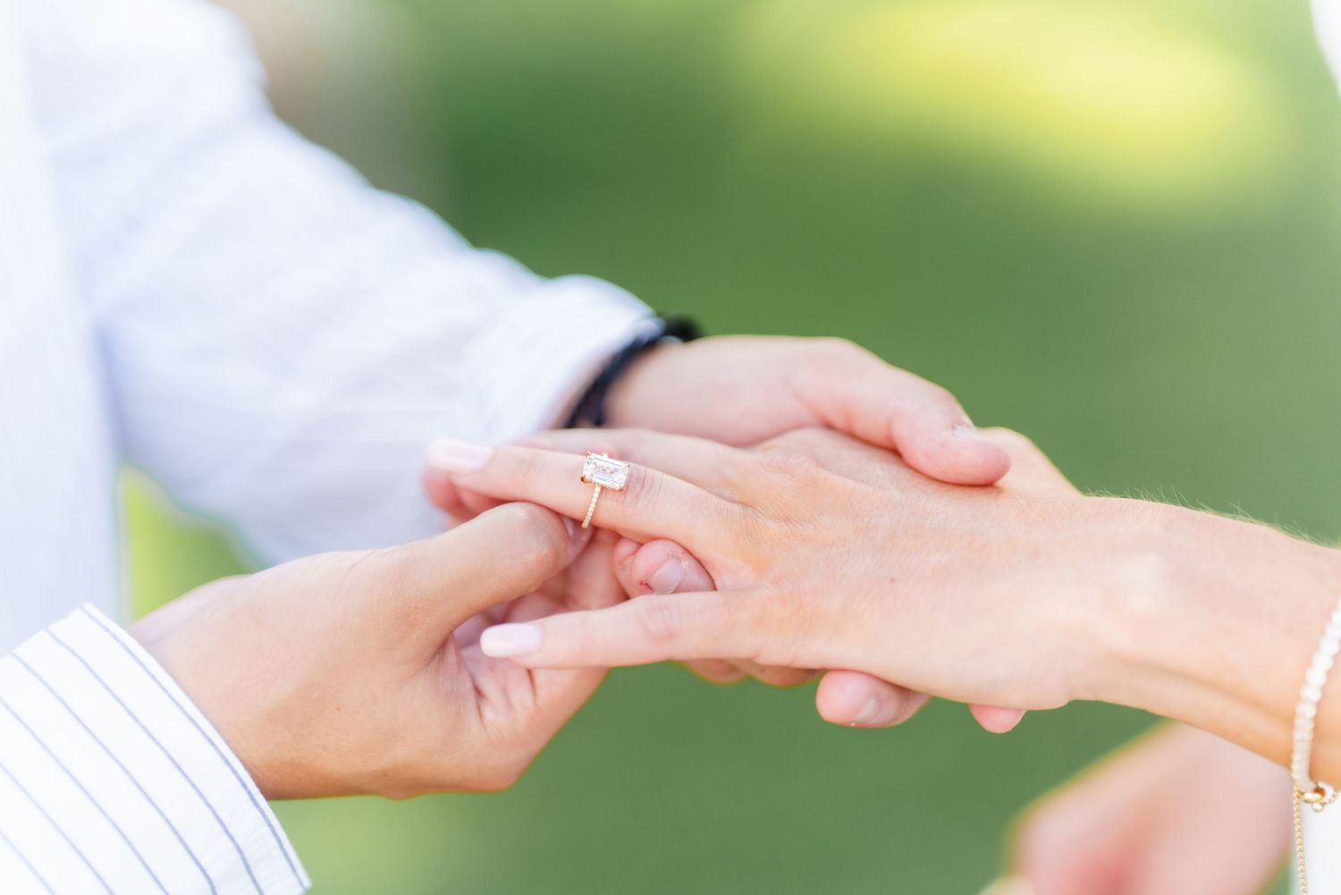 Close up of hands reaching out to connect with each other against a soft blurred green background.