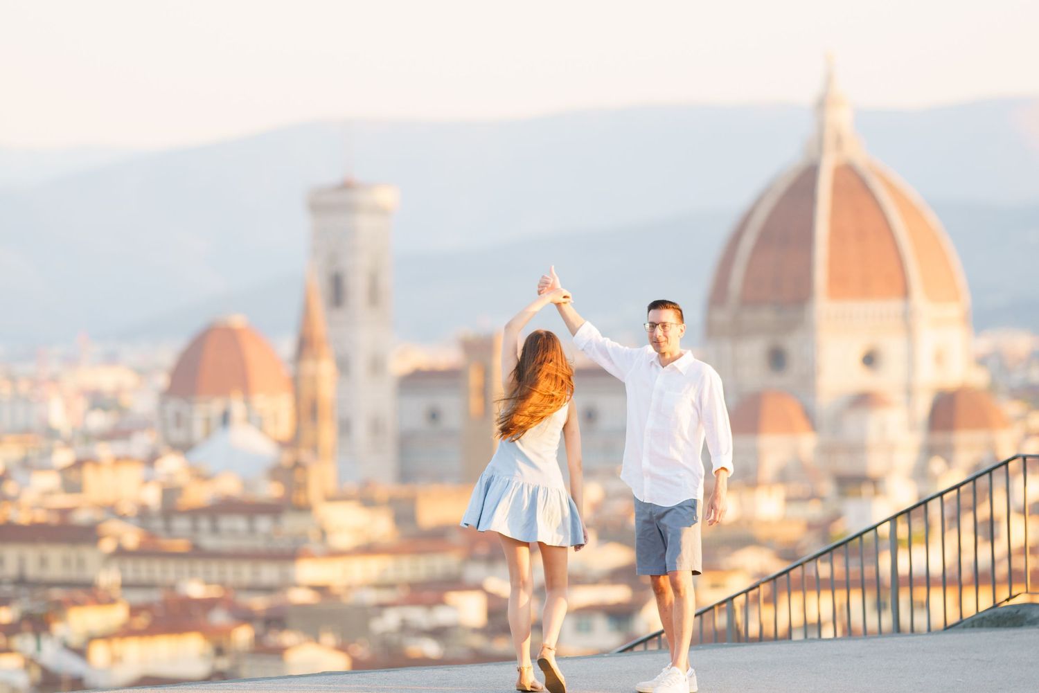 photographer Florence A couple poses on a viewpoint overlooking Florence, Italy with the iconic Duomo cathedral dome in the background.