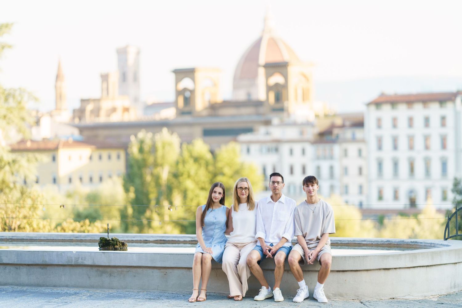 A group sits together on a stone wall overlooking Florence, Italy with the historic Basilica di Santa Croce in the background.