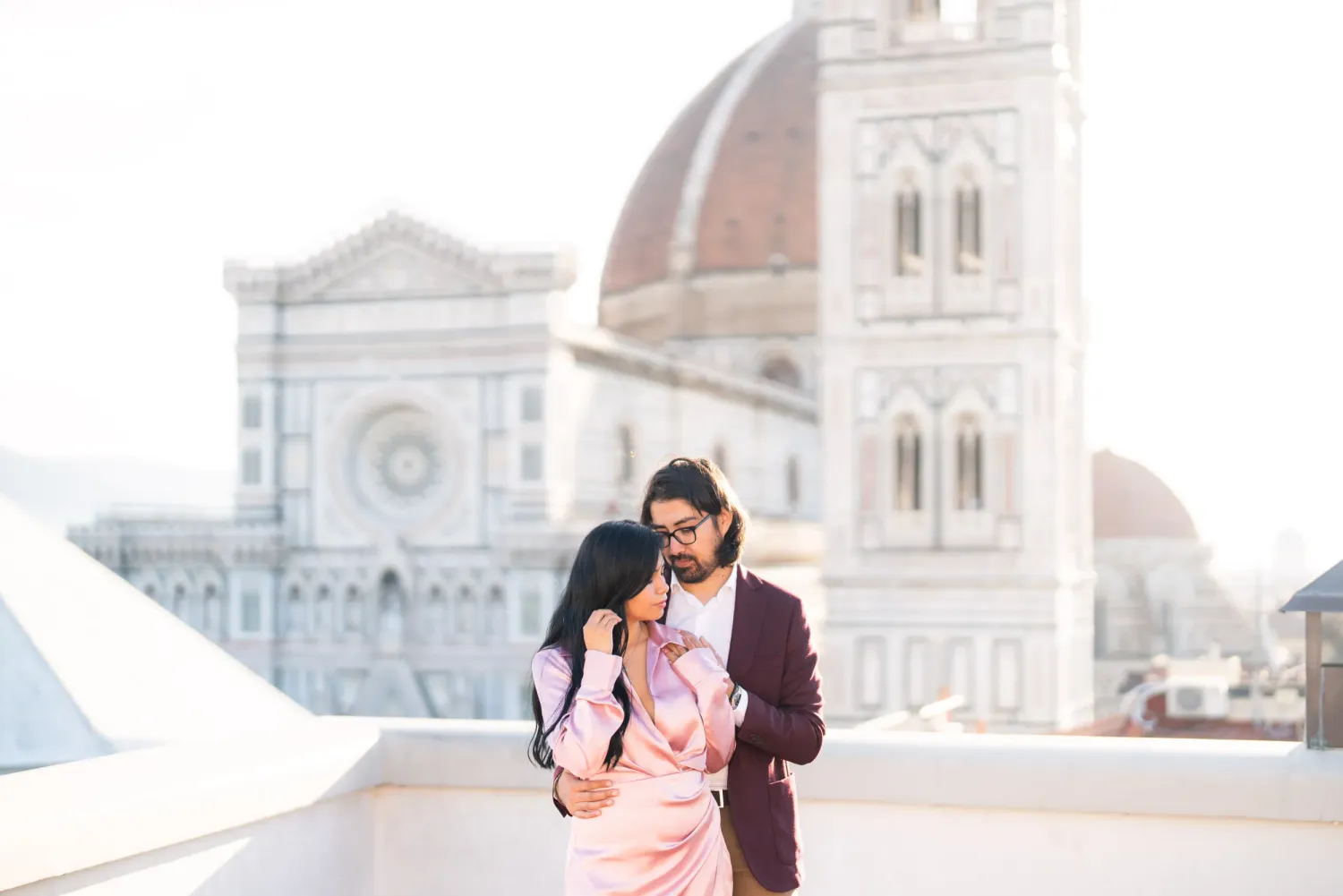 Romantic couple embraces in front of Florence Cathedral in Italy during a dreamy sunset photoshoot.