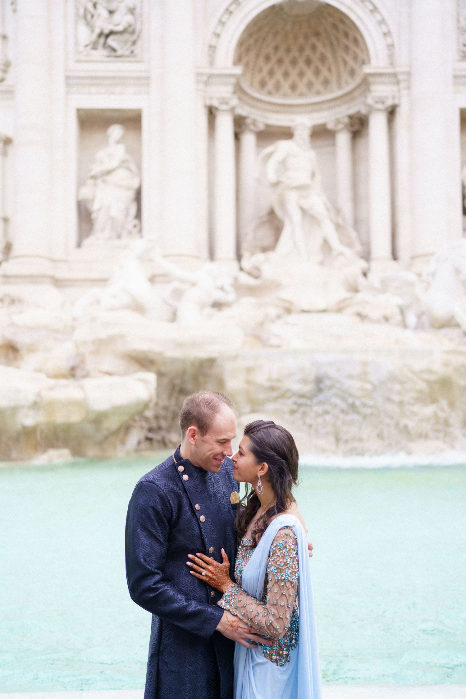 Intimate moment captured at Trevi Fountain with couple in fusion wedding attire.