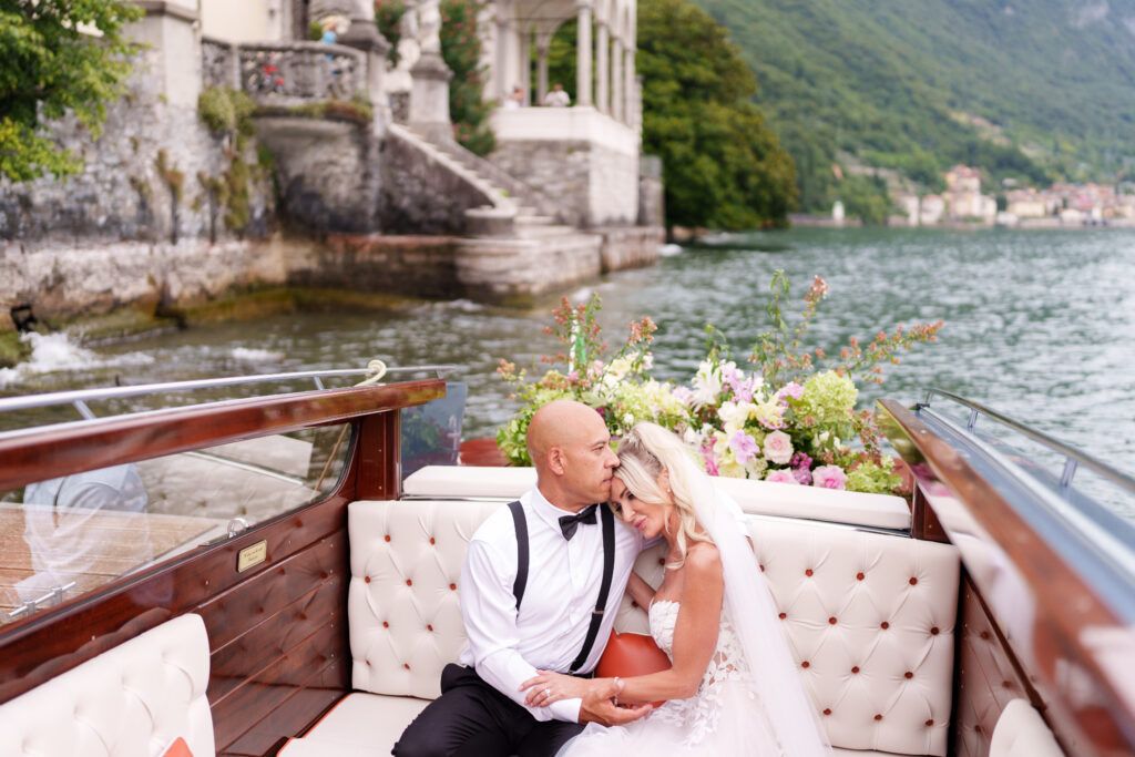Elegant wedding couple shares intimate moment on tufted sofa overlooking Lake Como and mountains.