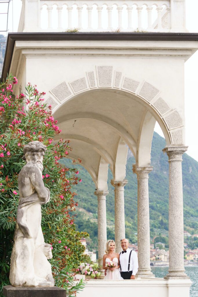 Romantic Italian villa terrace with arched columns and flowering bushes overlooking Lake Como.