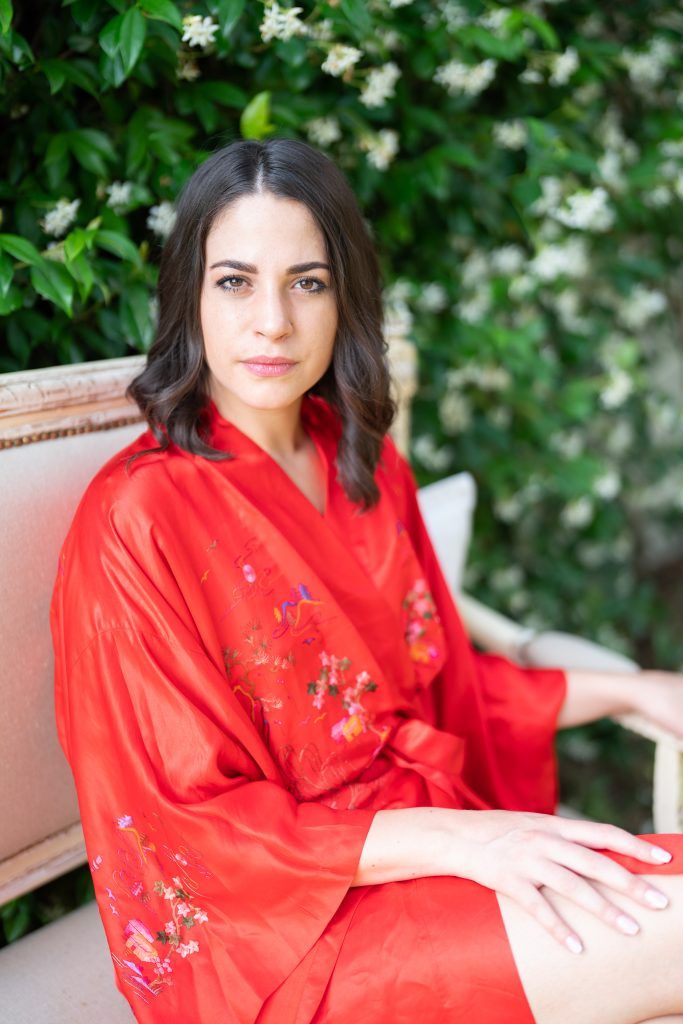 Portrait in garden setting wearing vibrant red floral robe.