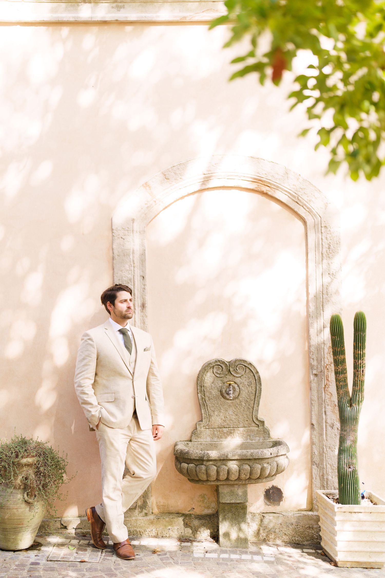 A series of artistic wedding photos against a white wall with decorative cacti and stone features.
