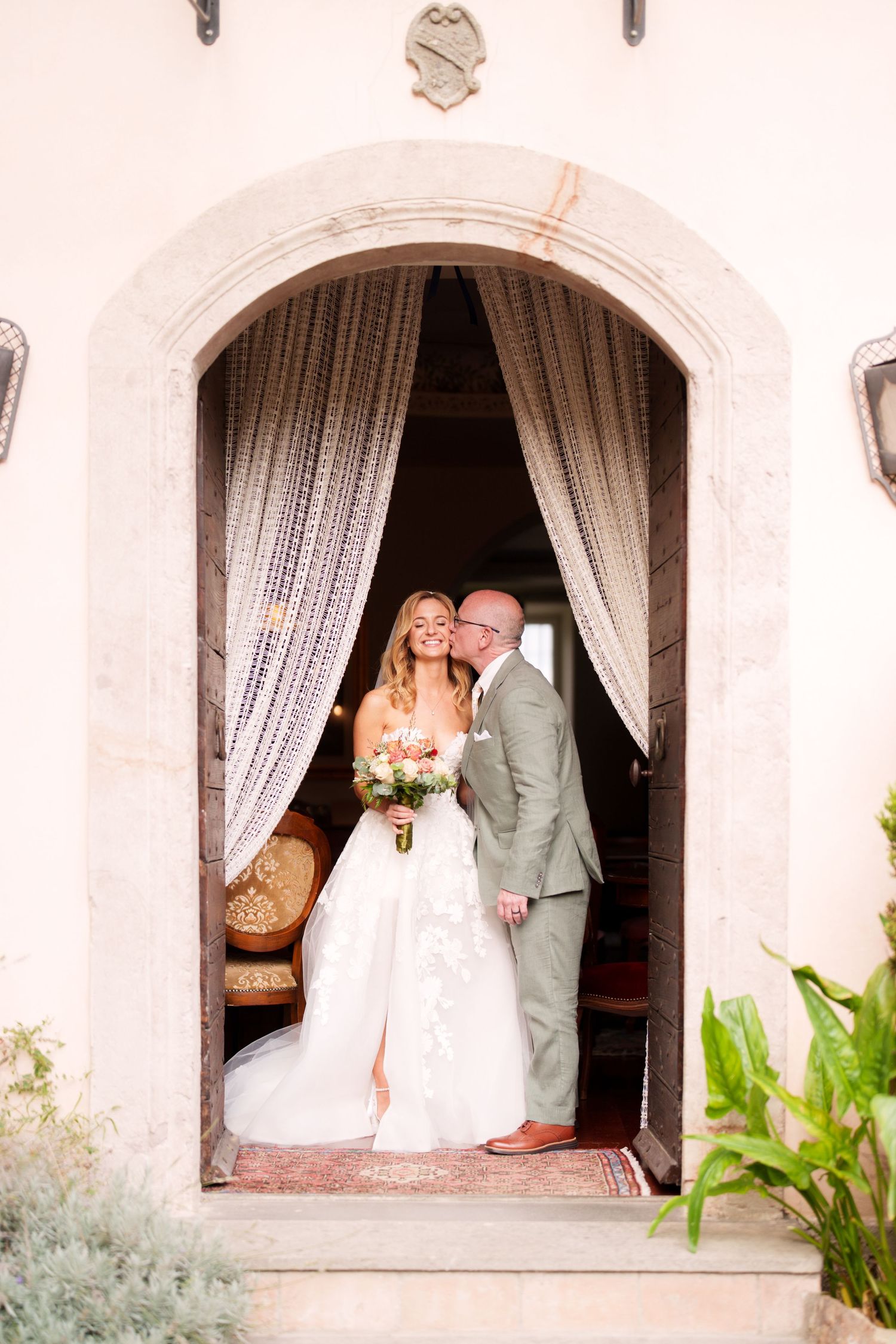 Wedding couple portraits taken through arched doorways with lace curtains.
