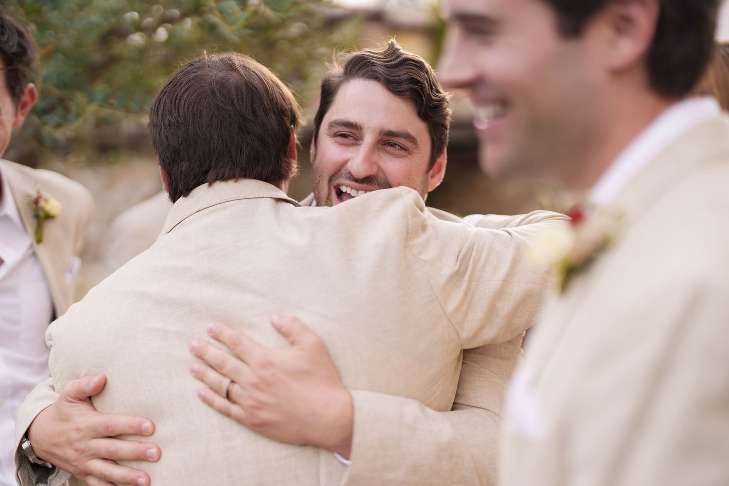 Group sharing embraces and hugs in light-colored formal attire.