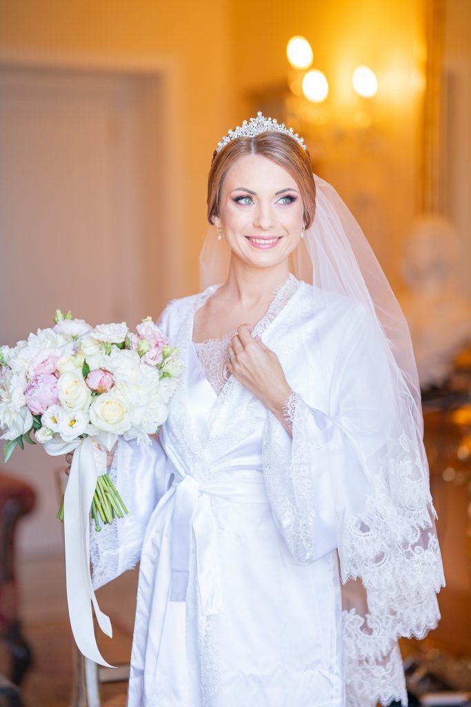 Bridal preparation scene with white lace robe and floral bouquet in elegant setting.