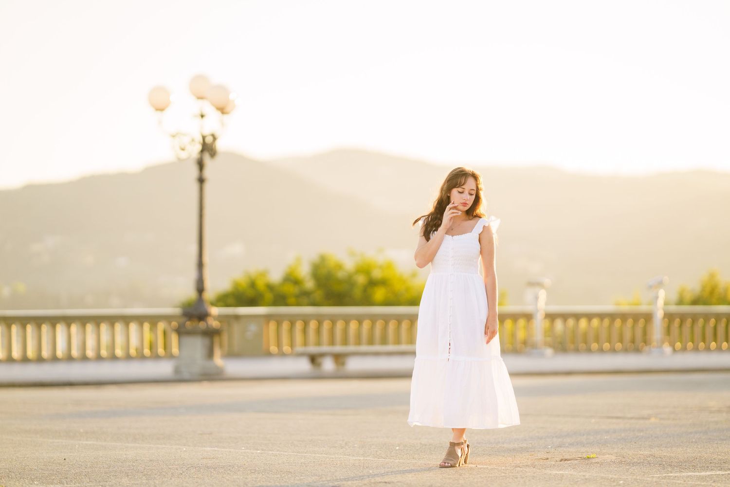 A series of romantic sunset engagement photos showing a couple in white outfits against a golden sky and railing backdrop.