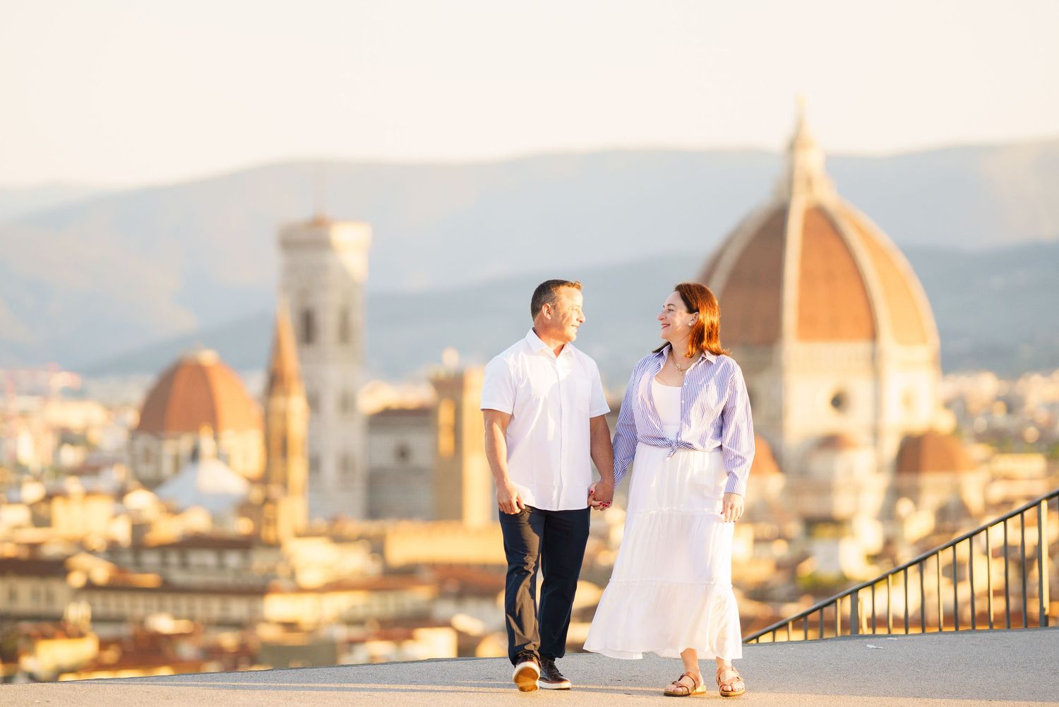 Couple enjoying a romantic sunset view of Florence's iconic skyline with the Duomo cathedral from a hilltop viewpoint.