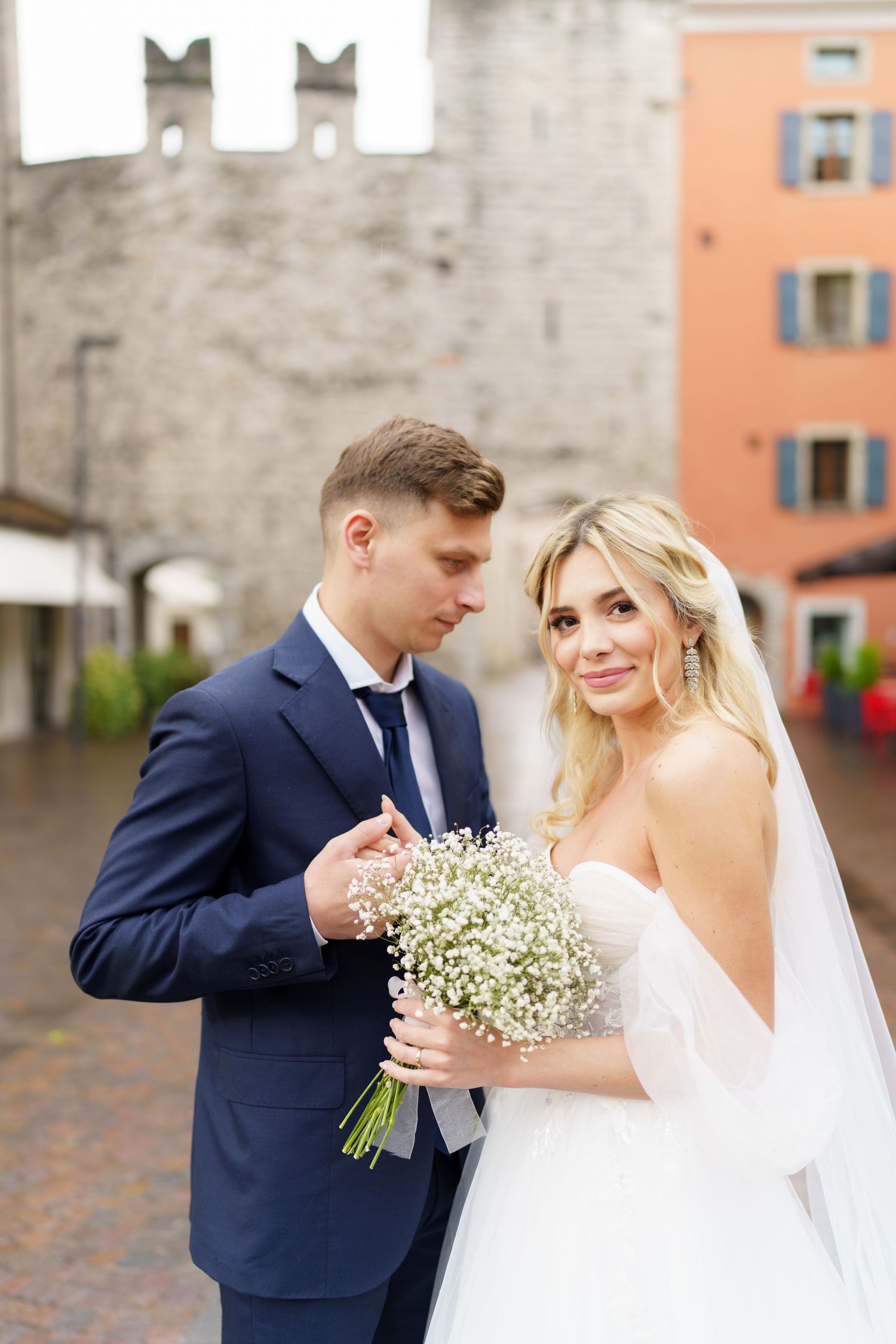 A romantic wedding couple shares tender moments in a series of photos with baby's breath bouquet and navy suit.