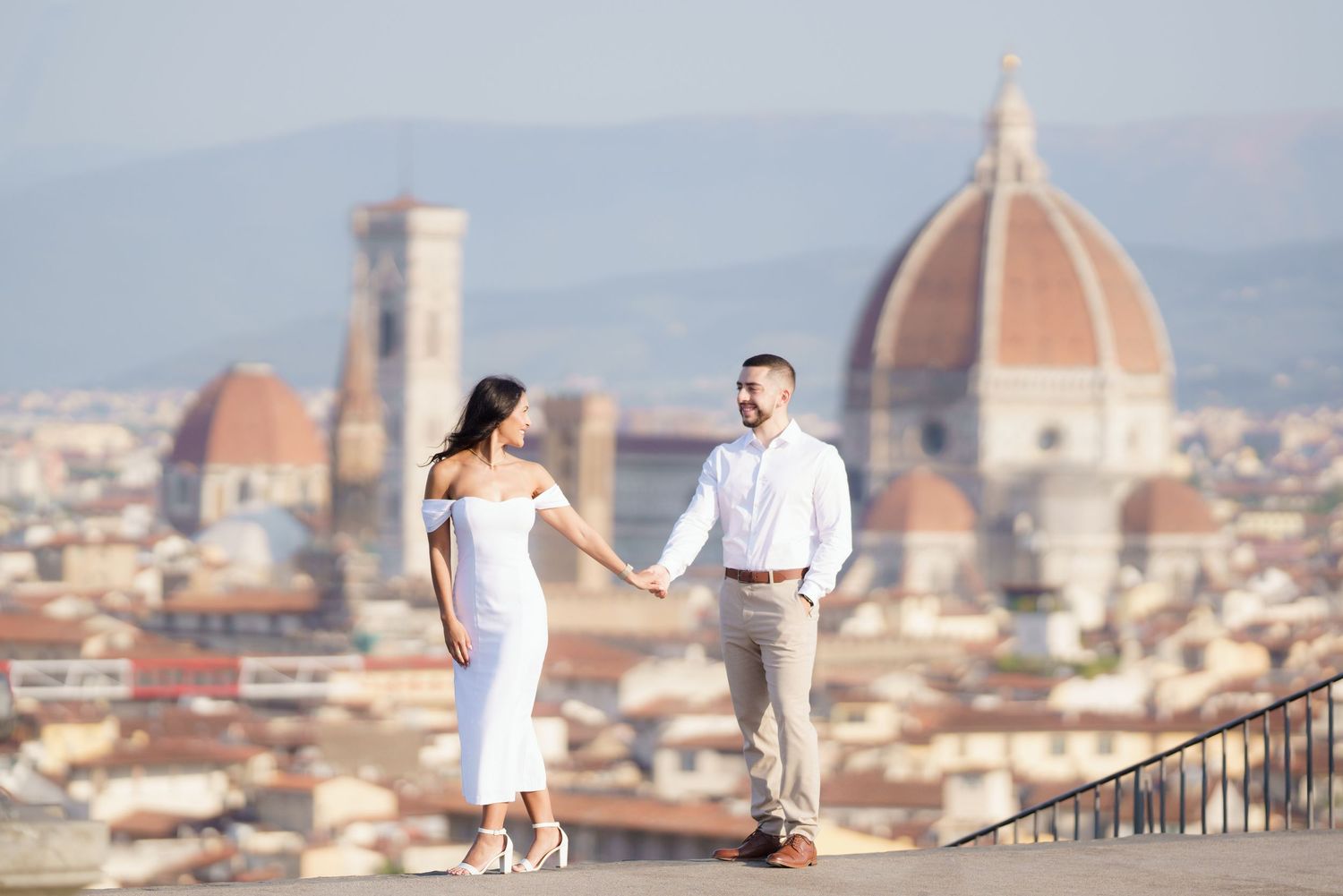 A couple poses for romantic wedding photos overlooking the historic skyline and Duomo cathedral of Florence, Italy.