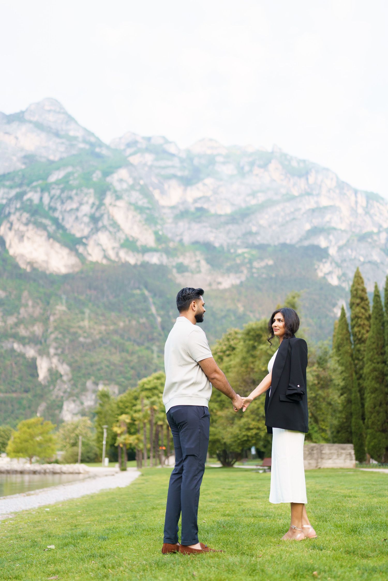 A romantic proposal scene unfolds on a grassy hillside with majestic mountain peaks in the background.
