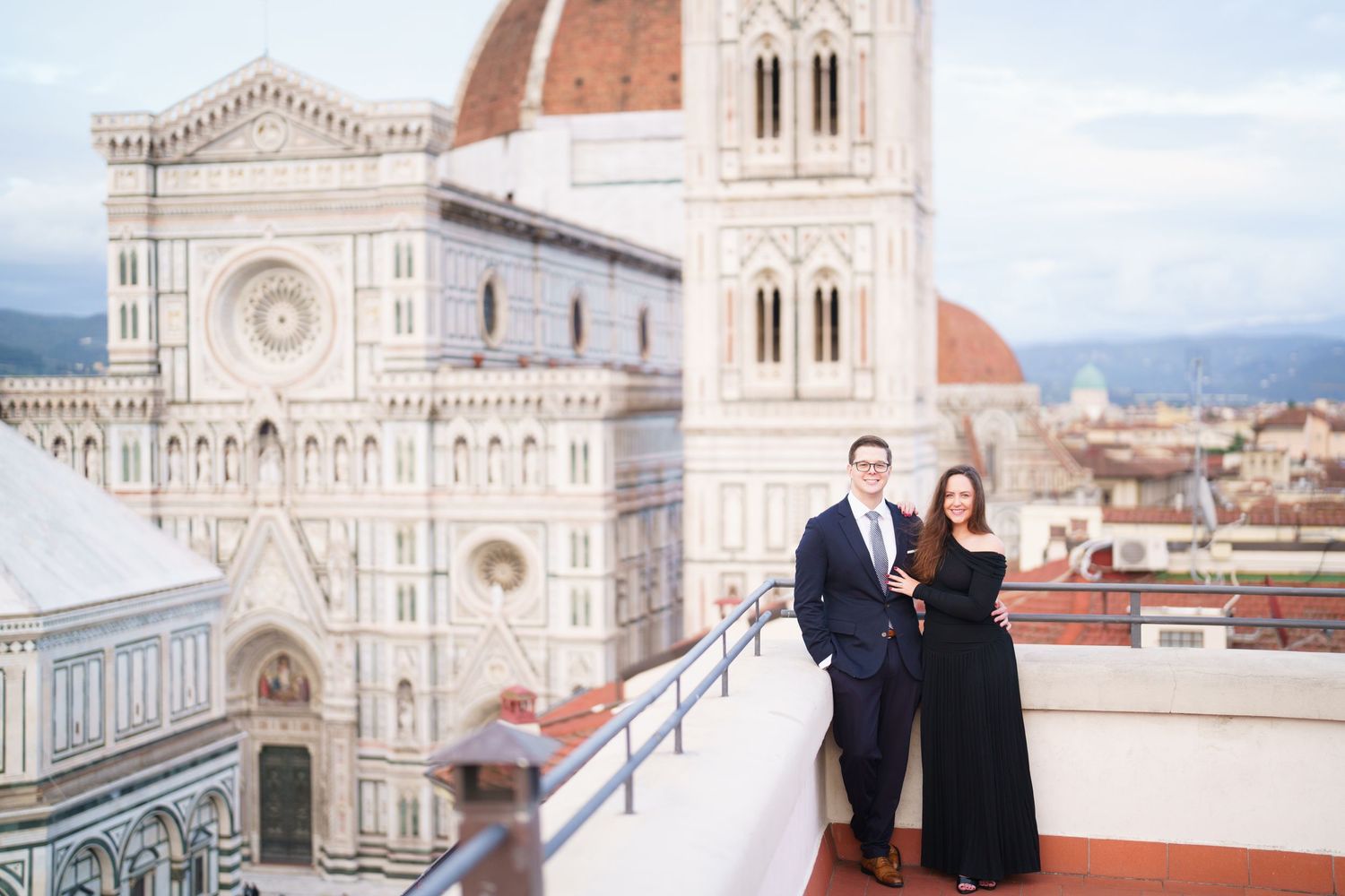 A couple poses in front of the Florence Cathedral and Duomo on a sunny day in Italy.