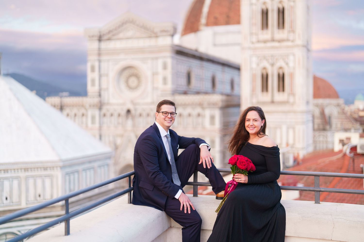 People pose for engagement photos in front of Florence Cathedral during sunset in Italy.
