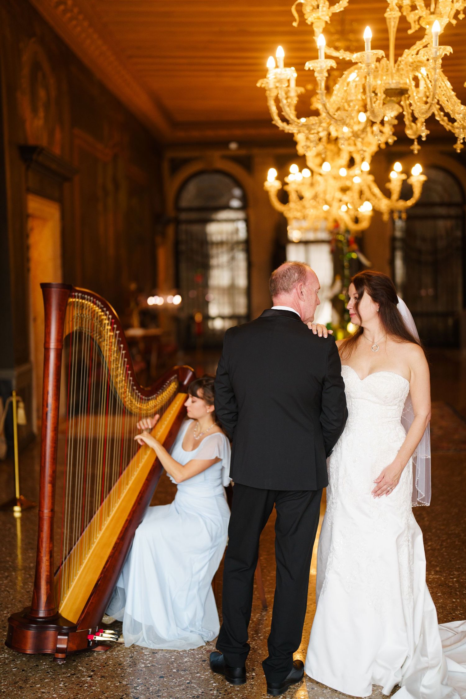 A series of elegant wedding photos featuring a harpist performing in an ornate ballroom with crystal chandeliers.