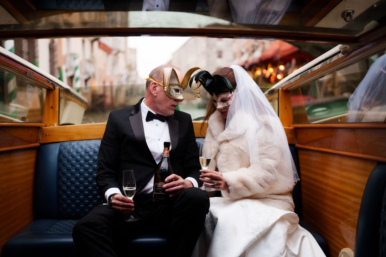 A couple shares an intimate moment in formal wedding attire while seated in a vintage boat interior.